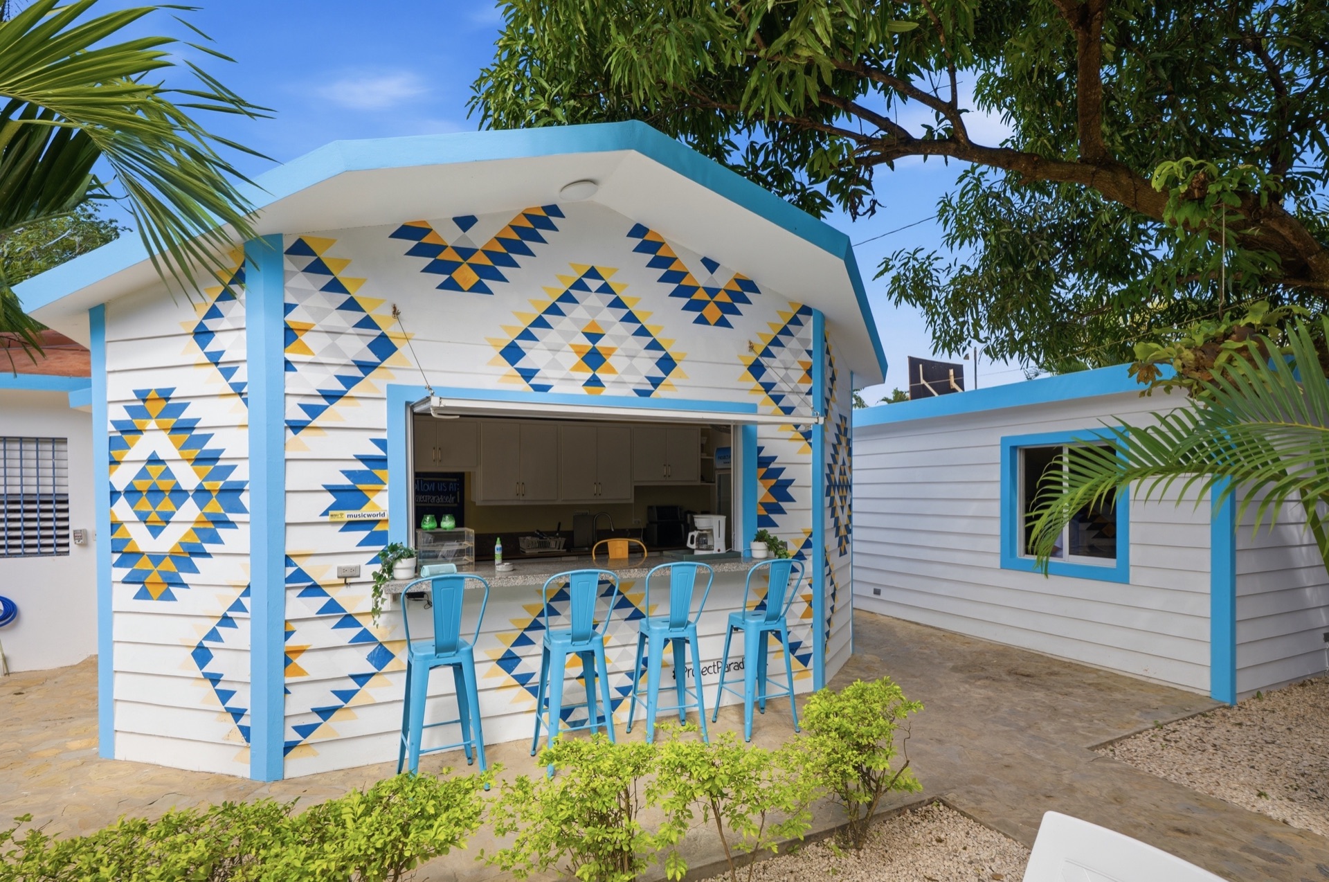 Outdoor bar with Aztec-pattern mural / Bar exterior con mural de patrón azteca