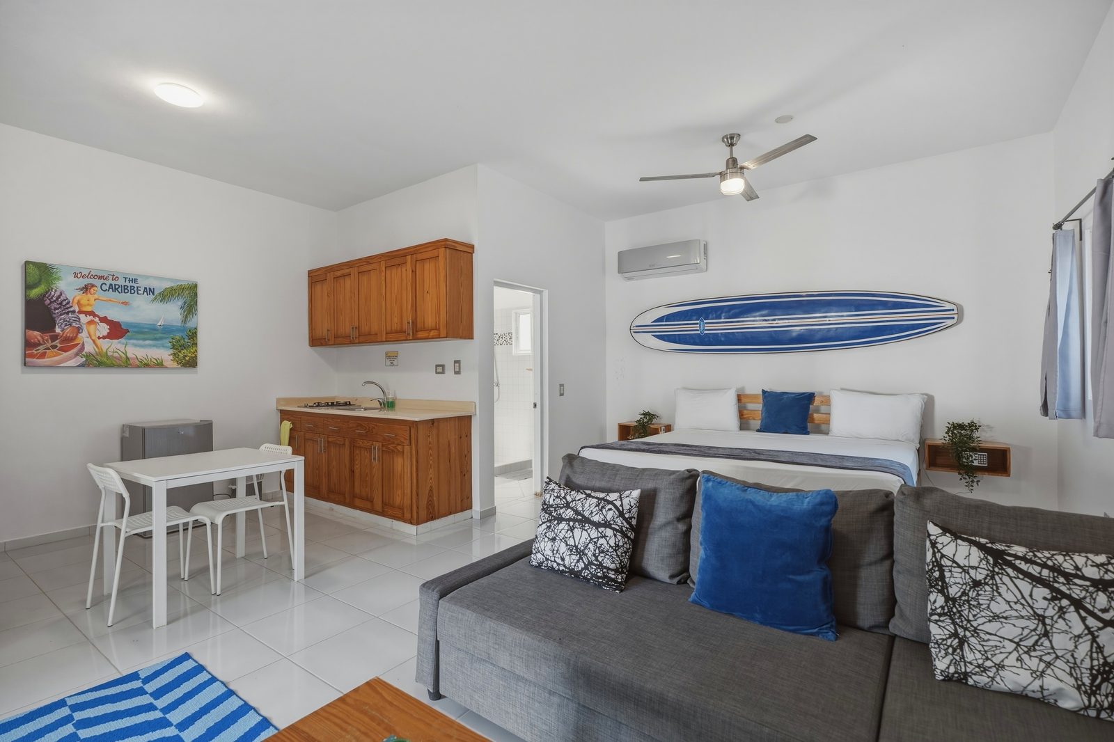 Studio with blue surfboard, king bed and sofa / Estudio con tabla de surf azul, cama king y sofá
