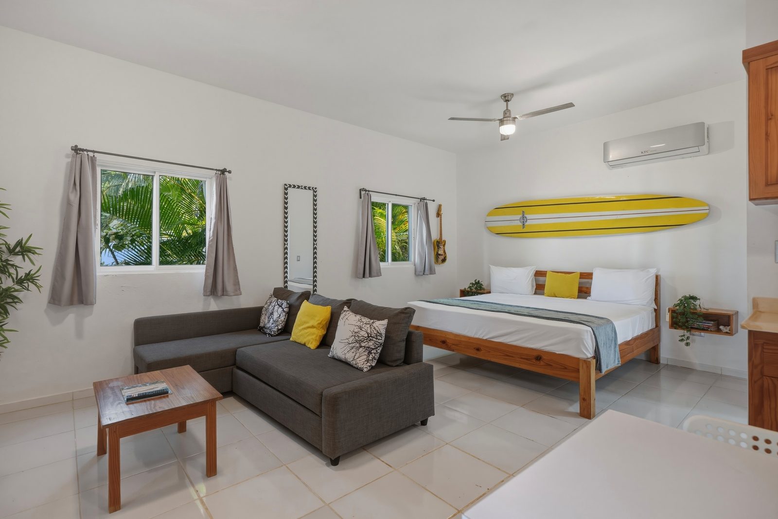 Studio lounge with yellow surfboard and kitchenette / Sala del estudio con tabla de surf amarilla y cocineta